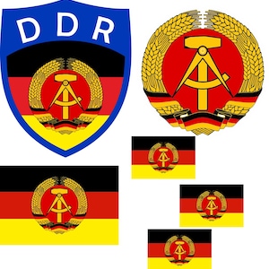 May include: An assortment of East German DDR emblems and flags. The emblems feature a hammer and compass within a wreath, set against red, black, and yellow backgrounds. The flags display the same emblem on a horizontal tricolour.
