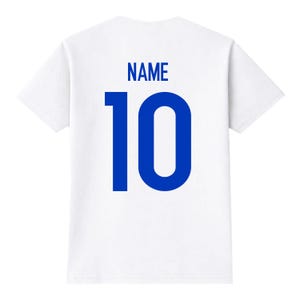 Pu&ograve; includere: T-shirt bianca con la scritta "NAME" in blu sopra il numero "10" in blu. La maglietta &egrave; bianca, con il testo e il numero in un carattere grassetto senza grazie.