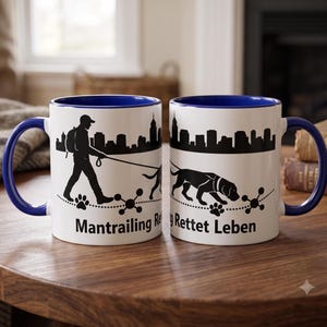 Peut inclure: Deux tasses en céramique blanche avec intérieur et anse bleu foncé. L'extérieur présente une silhouette noire d'une personne promenant un chien devant une ligne d'horizon urbaine, des empreintes de pattes et le texte Mantrailing Rettet Leben.