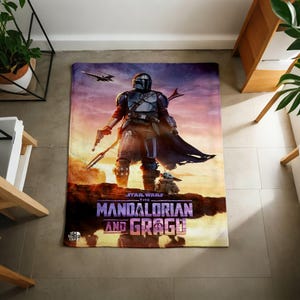 Pode incluir: Uma manta retangular com tema Star Wars com The Mandalorian e Grogu. A manta exibe uma cena com o Mandaloriano segurando um blaster, Grogu e uma nave espacial contra um fundo de p&ocirc;r do sol. As palavras "The Mandalorian and Grogu" s&atilde;o impressas.