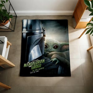 Pode incluir: Um cobertor retangular com tema Star Wars com o capacete do Mandaloriano e Grogu. O cobertor tem o texto "THE MANDALORIAN AND GROGU" em verde e branco, com texto adicional em espanhol. O cobertor est&aacute; em um ch&atilde;o de ladrilhos.