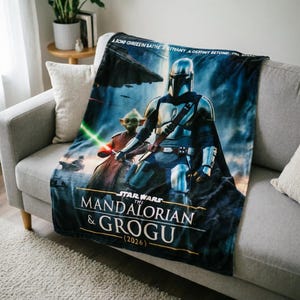 Pode incluir: Um cobertor com o tema Star Wars com The Mandalorian e Grogu. O cobertor tem um fundo azul com imagens dos personagens e o texto "The Mandalorian & Grogu (2026)". O cobertor est&aacute; sobre um sof&aacute; cinza.