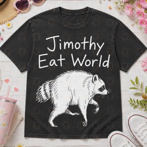 May include: A black short-sleeve t-shirt with a white graphic of a raccoon and the text "Jimothy Eat World" printed in white. The shirt features a crew neckline and a washed-out, vintage-style fabric texture throughout the garment.