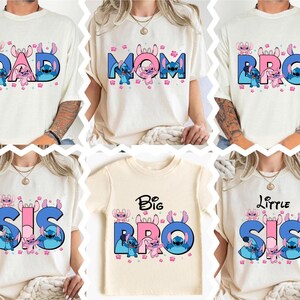 May include: Cream-colored t-shirts with family-themed designs. The shirts feature the words "DAD", "MOM", "BRO", "SIS", "Big BRO", and "Little SIS" in blue and pink, with cartoon characters.