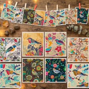 Könnte beinhalten: Eine Sammlung quadratischer Kunstdrucke mit farbenfrohen Vogelillustrationen und Blumenmustern. Jeder Druck zeigt detaillierte Vogelmotive, die auf Zweigen sitzen oder von botanischen Elementen umgeben sind, dargestellt in lebendigen Farben auf hellen und dunklen Hintergründen.