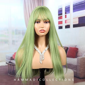 Puede incluir: Peluca verde claro con cabello largo y liso y flequillo, exhibida en una cabeza de maniquí. La peluca está peinada con una raya en medio y un flequillo romo. Un collar plateado con un diseño en cascada está alrededor del cuello del maniquí. La marca "HAMMADICOLLECTIONS" está en la parte inferior.