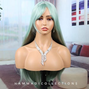 May include: A mannequin head displaying a long, mint-green wig with a side bang. The mannequin is adorned with a sparkling silver necklace and matching earrings. The text "HAMMADICOLLECTIONS" is visible at the bottom of the image.