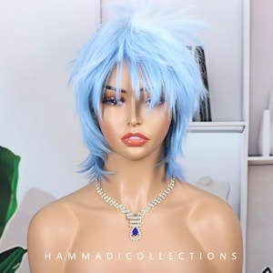 May include: A mannequin head with a light blue, layered wig. The wig has a spiky, textured style. The mannequin is wearing a sparkling necklace with a large, blue teardrop-shaped pendant. The text "HAMMADICOLLECTIONS" is at the bottom.