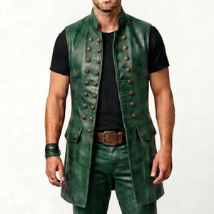 Pode incluir: Um colete de couro verde com design de abotoamento duplo e numerosos bot&otilde;es dourados. O colete tem gola alta e dois bolsos frontais. O modelo usa uma camisa preta e cal&ccedil;as de couro verde. O colete tem cerca de 76 cm de comprimento.