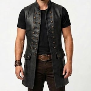 Pode incluir: Um colete de couro preto com gola mandarim e fecho de bot&otilde;es de dupla abotoadura. O colete apresenta dois bolsos frontais e &eacute; usado sobre uma camiseta preta e cal&ccedil;as marrons. Design vintage de inspira&ccedil;&atilde;o militar.