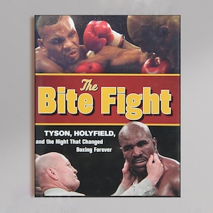 Può includere: Stampa incorniciata raffigurante una scena di un incontro di boxe. Il titolo "The Bite Fight" è visualizzato in grandi lettere gialle su sfondo rosso. La stampa include immagini di Mike Tyson ed Evander Holyfield, con testo sottostante.