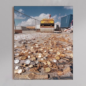 Op de afbeelding: Een afbeelding van een grote verzameling gouden horloges verspreid over een betonnen oppervlak. Een wals met de tekst "POES RENTALS" is op de achtergrond te zien. De horloges hebben verschillende bandstijlen en wijzerplaatontwerpen.