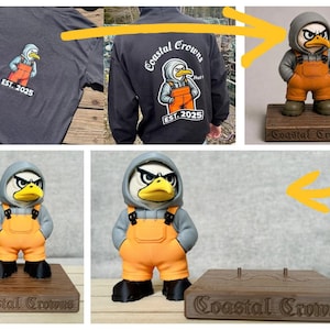 May include: A grey hoodie and t-shirt featuring a graphic of an eagle wearing a grey hoodie and orange overalls with the text Coastal Crowns EST. 2025, alongside a matching eagle figurine on a wooden base with the text Coastal Crowns engraved.