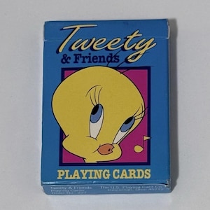 May include: A blue box of Tweety & Friends playing cards. The box features a yellow Tweety Bird character with blue eyes and a pink background. The words "Tweety & Friends" are in a yellow script font above the character.