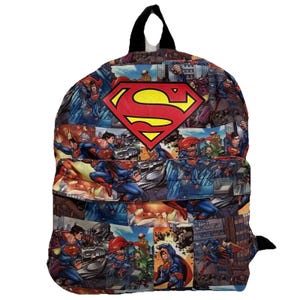 May include: A Superman-themed backpack featuring a collage of comic book panels. The backpack has a large red and yellow Superman logo on the front. The background is a mix of blue, red, and gray tones, with a black handle and straps.