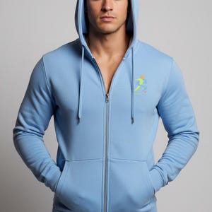 Puede incluir: Una sudadera con capucha y cremallera en color azul claro, con capucha y cordones a juego, mangas largas y dos bolsillos delanteros. En el lado izquierdo del pecho lleva un pequeño gráfico colorido de una figura estilizada en movimiento.