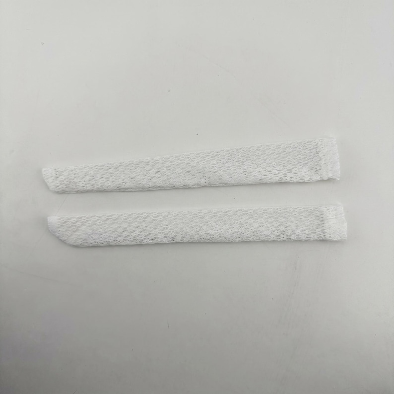 Puede incluir: Dos fundas tubulares de malla blanca, alargadas y con una textura fina de tejido abierto. Cada pieza presenta un dise&ntilde;o recto y estrecho con bordes acabados en ambos extremos, ofreciendo una apariencia consistente, ligera y semitransparente.