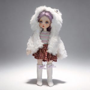 May include: A doll wearing a white faux fur hooded coat, a striped shirt, and a plaid skirt. The doll has purple hair and is wearing white boots with lavender bows. The doll is standing in front of a gray background.