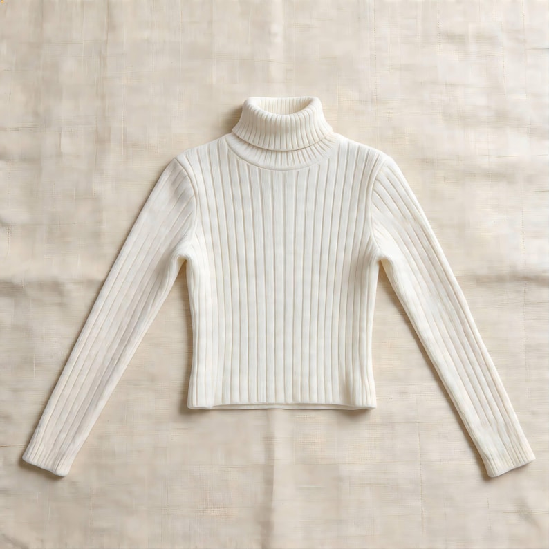 May include: A cream-colored turtleneck sweater with long sleeves. The sweater has a ribbed knit design and is made of a soft, warm material. The turtleneck is folded over and the sleeves are extended.