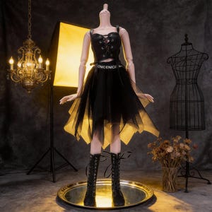 May include: A black doll dress with a lace-up bodice, a layered skirt with a yellow underlay, and black lace-up boots. The dress features the text "ENICENICE" on the waist. The doll is displayed on a reflective surface.