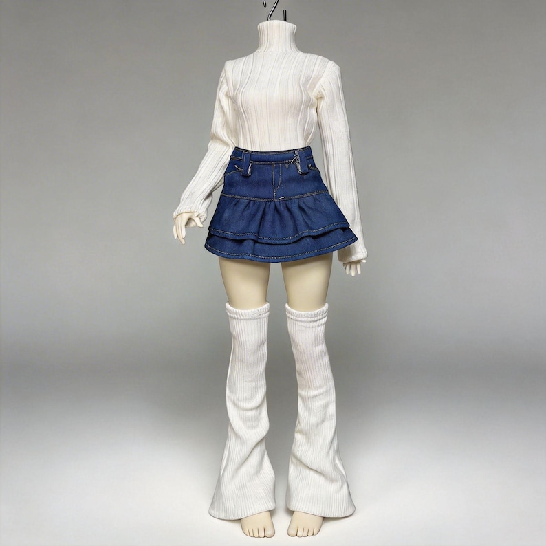 May include: A white ribbed turtleneck sweater paired with a denim mini skirt and white leg warmers. The skirt has a layered ruffle design. The outfit is displayed on a mannequin against a neutral background.