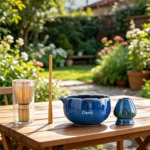 May include: A matcha tea set featuring a bamboo whisk in a clear cylindrical case, a long bamboo scoop, a deep blue ceramic bowl with a scalloped rim and the name David printed on the side, and a matching blue ceramic whisk holder.