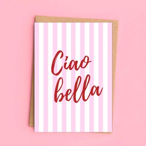 Könnte beinhalten: Eine rechteckige Grußkarte mit einem vertikalen Muster aus abwechselnden weißen und hellrosa Streifen. Der Text Ciao bella ist mittig in einer fetten, roten Schreibschrift aufgedruckt. Die Karte steckt in einem braunen Papierumschlag.