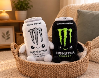 May include: Two plush toys shaped like energy drink cans, one white with the text ZERO SUGAR and MONSTER ENERGY ULTRA WHITE, and one black with the text TAURINE+GINSENG and MONSTER ENERGY, both featuring embroidered monster logos and faces.