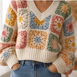 May include: A cream-colored, V-neck sweater with a patchwork design. The sweater features colorful crochet squares in shades of pink, yellow, blue, and green. The cuffs and hem are ribbed, and the sweater has long sleeves.