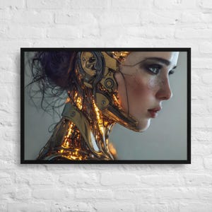 May include: Framed artwork depicting a person with a futuristic, golden, mechanical augmentation on the head and neck. The person has fair skin, dark hair, and is set against a neutral background. The artwork is in a black frame.