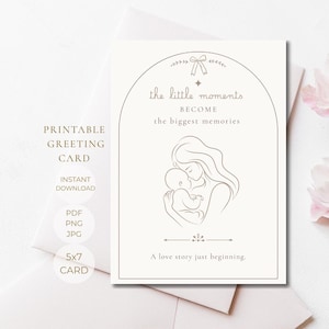 Könnte beinhalten: Eine weiße Grußkarte mit einer Strichzeichnung einer Person, die ein Baby in einem Bogenrahmen hält. Der Text lautet: the little moments BECOME the biggest memories und A love story just beginning. Ein kleines Schleifensymbol befindet sich oben.