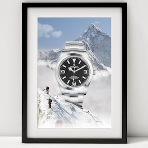 May include: Framed print featuring a Rolex Explorer watch with a black dial, set against a snowy mountain backdrop. The watch has a silver band and is positioned above two figures climbing a mountain. The print includes the text "214 270 EXPLORER" and the Rolex logo.