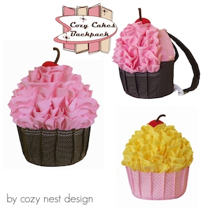 May include: A collection of cupcake-shaped backpacks. The backpacks feature pink, yellow, and brown colors, with a cherry on top. The text "Cozy Cakes Backpack" is displayed in a retro font. The bottom of the image reads "by cozy nest design".