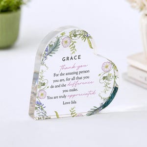 May include: A heart-shaped acrylic block with floral accents and the words "GRACE Thank you" printed in black and pink. The text continues with a message of appreciation, signed "Love Isla."