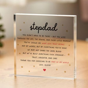 May include: A clear acrylic block with the word "stepdad" in a handwritten font. The block contains a heartfelt message with gold star accents and a red heart. The text expresses gratitude and love.