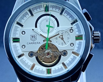 Reloj de hombre Tag Heuer Carrera Chrono automático vintage con esfera blanca, correa de caucho negra, tourbillon de corazón abierto, fondo transparente y caja de acero inoxidable.