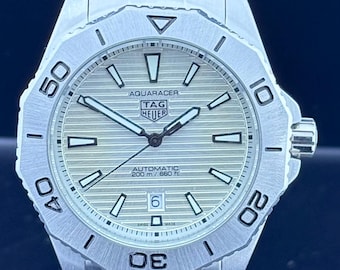 Reloj de hombre Tag Heuer Aqua-Racer automático vintage con esfera blanca, caja plateada, caja y brazalete de acero inoxidable, bisel giratorio y fecha.