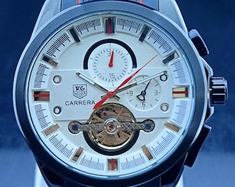 Reloj de hombre Tag Heuer Carrera Chrono automático vintage con esfera blanca, correa de caucho negra, tourbillon de corazón abierto, fondo transparente y caja de acero inoxidable.