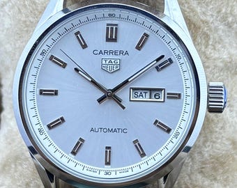 Reloj de pulsera vintage Tag Heuer de movimiento automático, esfera blanca, correa de cuero marrón, fondo transparente, fecha/día funcional, acero inoxidable para hombre.