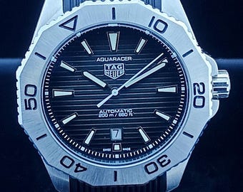 Reloj de hombre Tag Heuer Aqua-Racer automático vintage con esfera negra, caja plateada, correa de caucho negra, bisel giratorio y fecha funcional, de acero inoxidable.