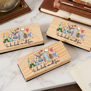 May include: Three wooden erasers with a black base. Each eraser features a colorful illustration of cartoon characters and the text "In da clerk, we all fam". The erasers are on a marble surface.