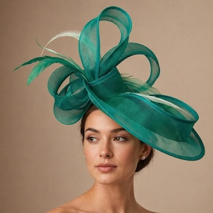 May include: A teal-colored formal hat with a wide brim and decorative ribbon loops. The hat features several green and white feathers. This elegant headwear is suitable for special occasions.