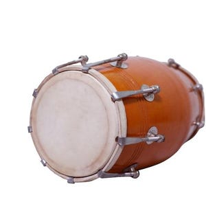 Op de afbeelding: Een bruine, houten djembe-drum met een wit drumvel. De drum heeft metalen hardware en staat tegen een witte achtergrond. Dit percussie-instrument wordt in verschillende muziekgenres gebruikt.