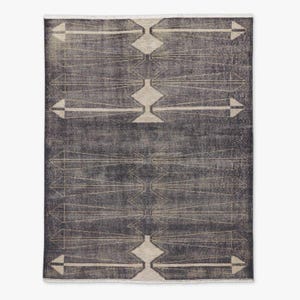 Peut inclure: Un tapis rectangulaire gris foncé avec un motif géométrique. Le design présente des formes de losanges et de flèches dans une couleur beige clair, créant un effet visuel contrasté. Les bords du tapis ont une bordure à franges.