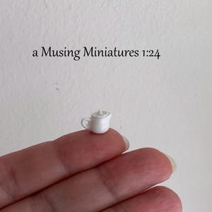 Peut inclure: Une minuscule théière en céramique blanche avec un couvercle et une petite anse, accompagnée du texte a Musing Miniatures 1:24 imprimé au-dessus. Cette théière est un modèle réduit miniature pour collection, avec une finition lisse et brillante.