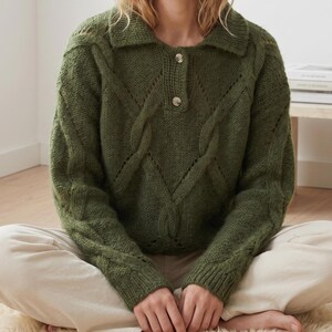 Peut inclure: Un pull en tricot vert olive à manches longues doté d'un col avec une patte de boutonnage à deux boutons. Le vêtement présente un motif en tricot torsadé texturé sur le devant et les manches, fini avec des poignets et un ourlet côtelés.