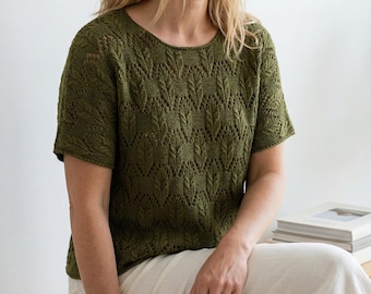 May include: Olive green short-sleeved knit top with a round neckline. The top features a detailed leaf pattern throughout the fabric. The model is wearing the top with light-coloured trousers. The top is a comfortable and stylish garment.
