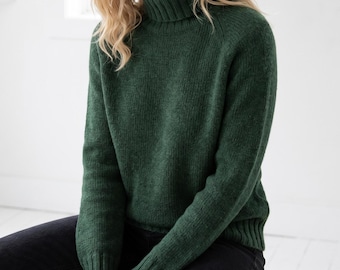 May include: A forest green long-sleeve jumper featuring a ribbed turtleneck collar, ribbed cuffs, and a ribbed hem. The knit garment has a textured appearance and is paired with black trousers, creating a simple and functional ensemble for daily wear.