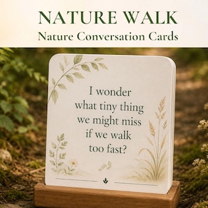 Könnte beinhalten: Eine quadratische weiße Karte mit abgerundeten Ecken in einem Holzständer. Die Karte zeigt grüne botanische Illustrationen und den Text: I wonder what tiny thing we might miss if we walk too fast? Darüber steht der Text NATURE WALK Nature Conversation Cards.