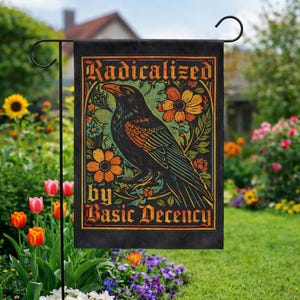 May include: Black garden flag featuring a stylized raven illustration with the text "Radicalized by Basic Decency." The design includes orange and yellow flowers and green foliage against a black background. The flag is displayed in a garden setting.